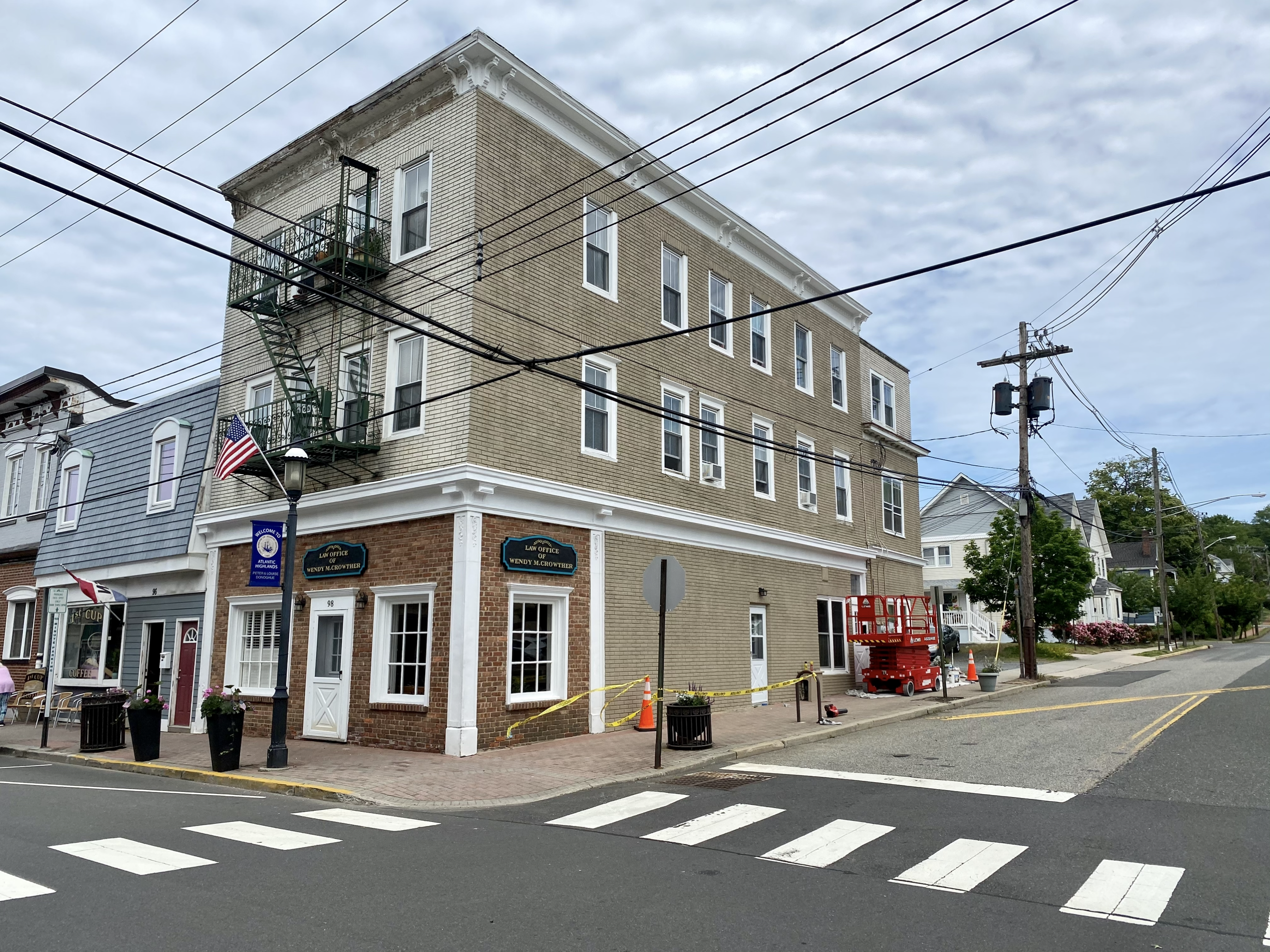 Multi-story commercial brick and siding building on street corner with scissor lift staged for exterior work