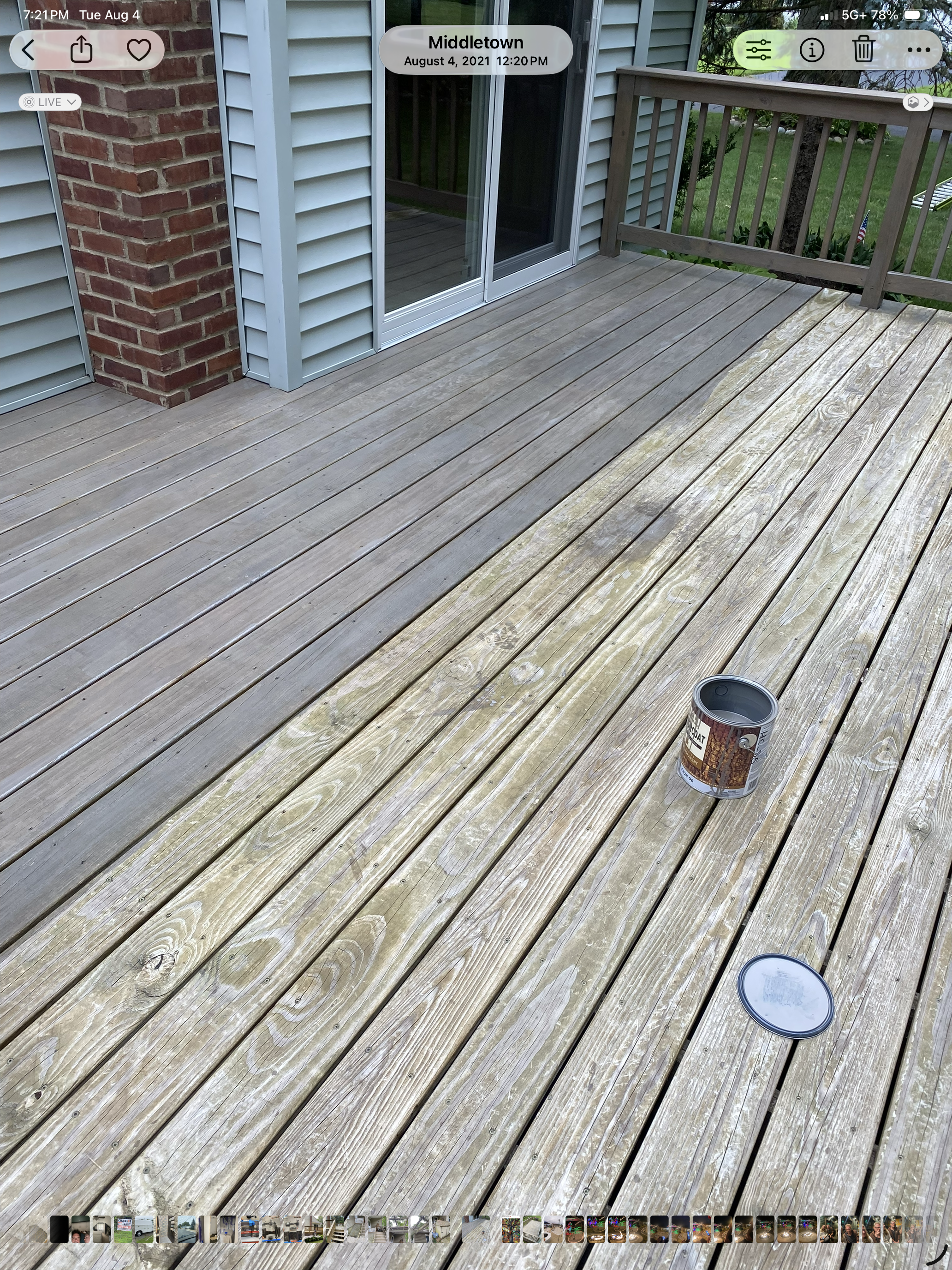 Residential deck mid-stain showing dramatic before and after split — weathered gray boards on right, freshly stained boards on left with stain can on deck