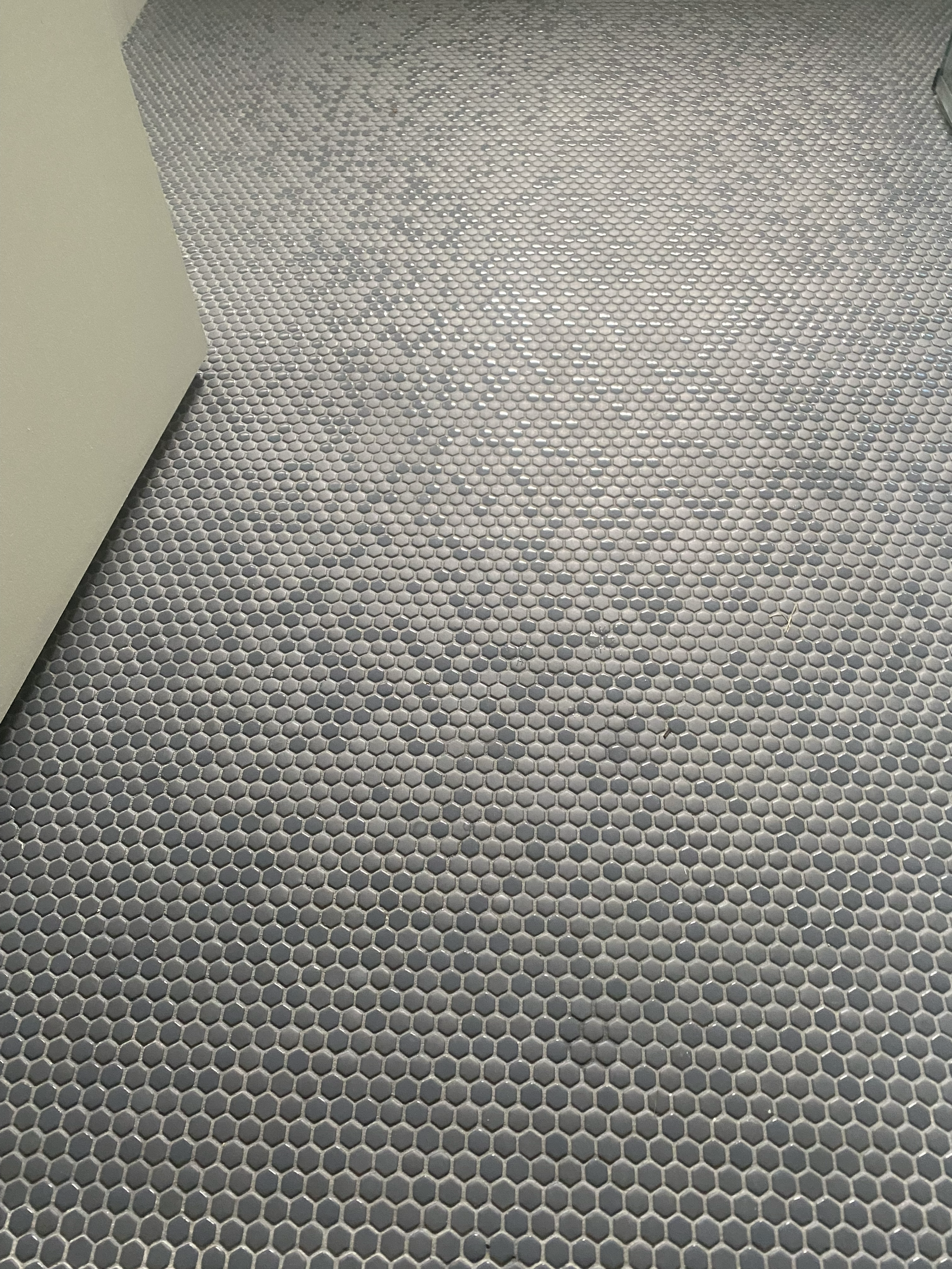Close-up of gray penny tile floor installation in bathroom remodel